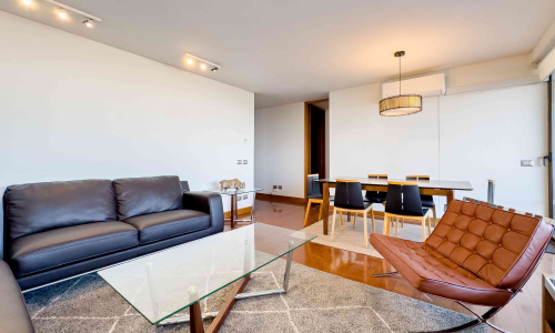 Dormitorio principal amoblado con cama de dos plazas, lámparas y clóset empotrado en departamento en El Golf.