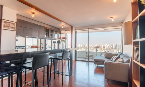 Cocina isla y living con vista despejada en departamento remodelado en Callao.