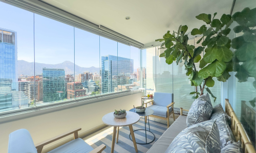 Living-comedor amoblado con vista al sur hacia la cordillera, en departamento de 3 dormitorios en El Golf, Las Condes.