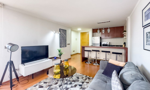 Living-comedor moderno con cocina americana y TV, en departamento amoblado de Las Condes.