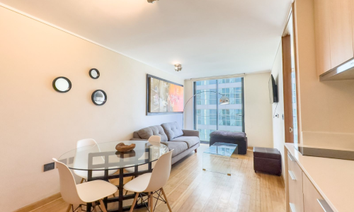 Living-comedor moderno y luminoso de departamento amoblado en El Golf, con cocina americana y decoración contemporánea.