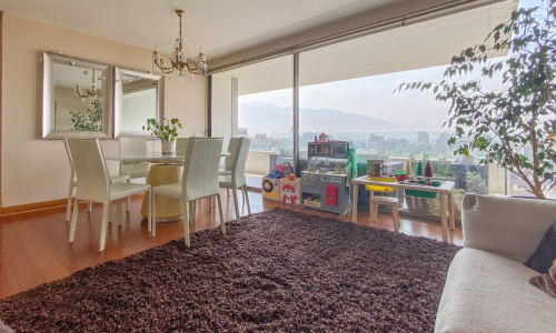 Living-comedor con salida a terraza y vista despejada hacia la cordillera en departamento sin amoblar en El Golf, Las Condes.